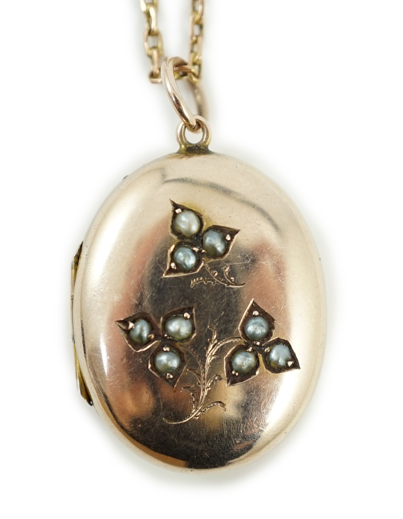 An Edwardian yellow metal and seed pearl set oval locket pendant, 25mm, on a 9ct chain, 47cm, gross weight 9.3 grams.